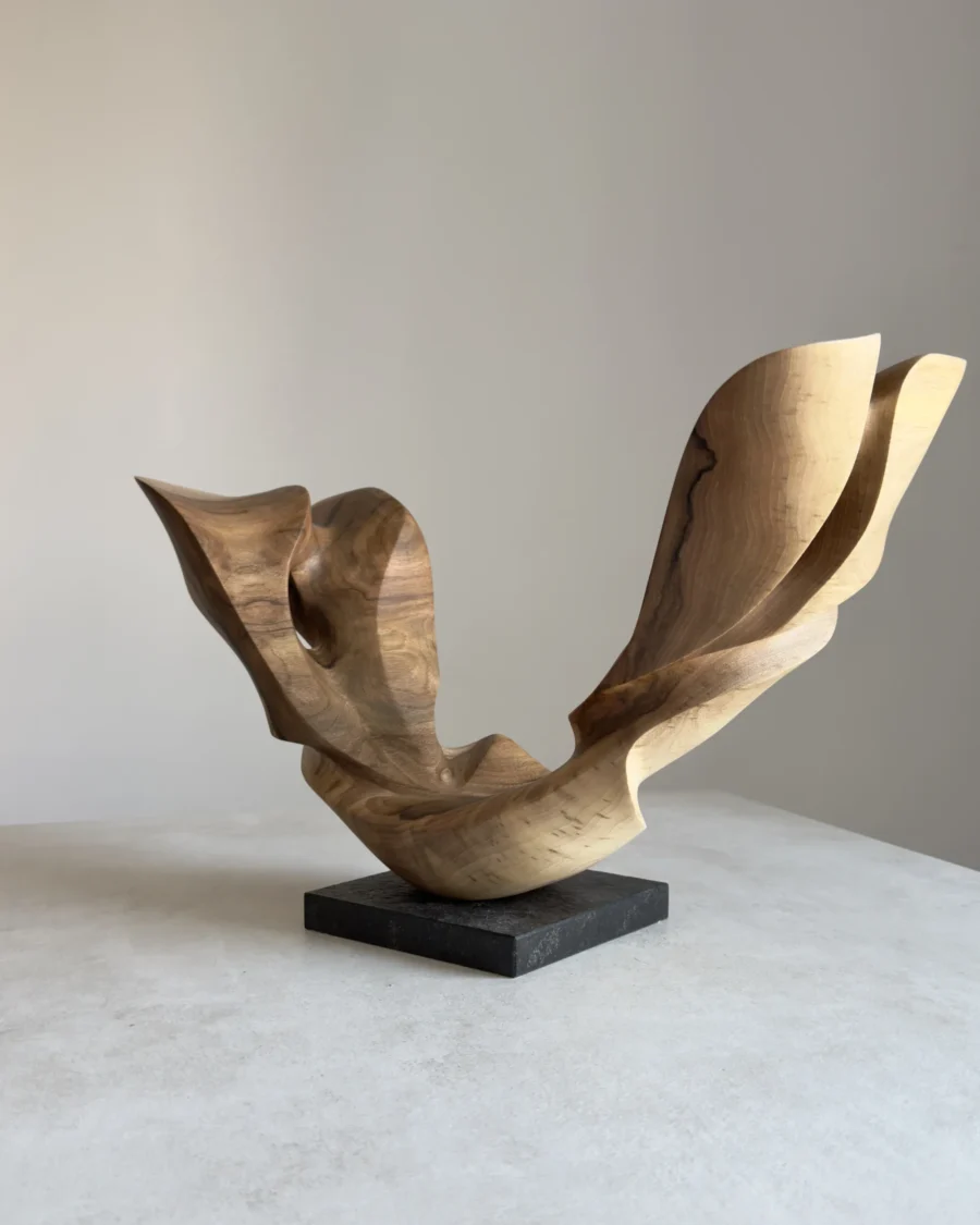 open-arc-walnut-wood-sculpture-main-ewebohome Hand carved walnut wood sculpture Open Arc displayed on a black granite base in natural light