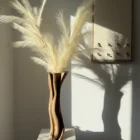 Abstract walnut wood vase with pampas grass, warm tones and soft organic silhouette in interior