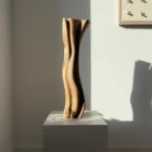 Walnut wood vase with dried grasses, tall hand-carved form casting organic shadow on wall
