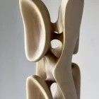 Detail of abstract wood sculpture Ivory Flow highlighting smooth curves and light reflection on walnut