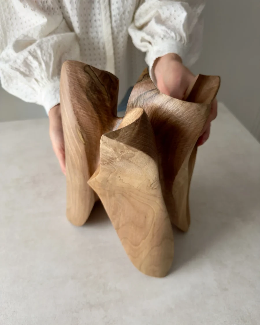 person holding modern abstract wood sculpture, handmade walnut piece with smooth flowing form