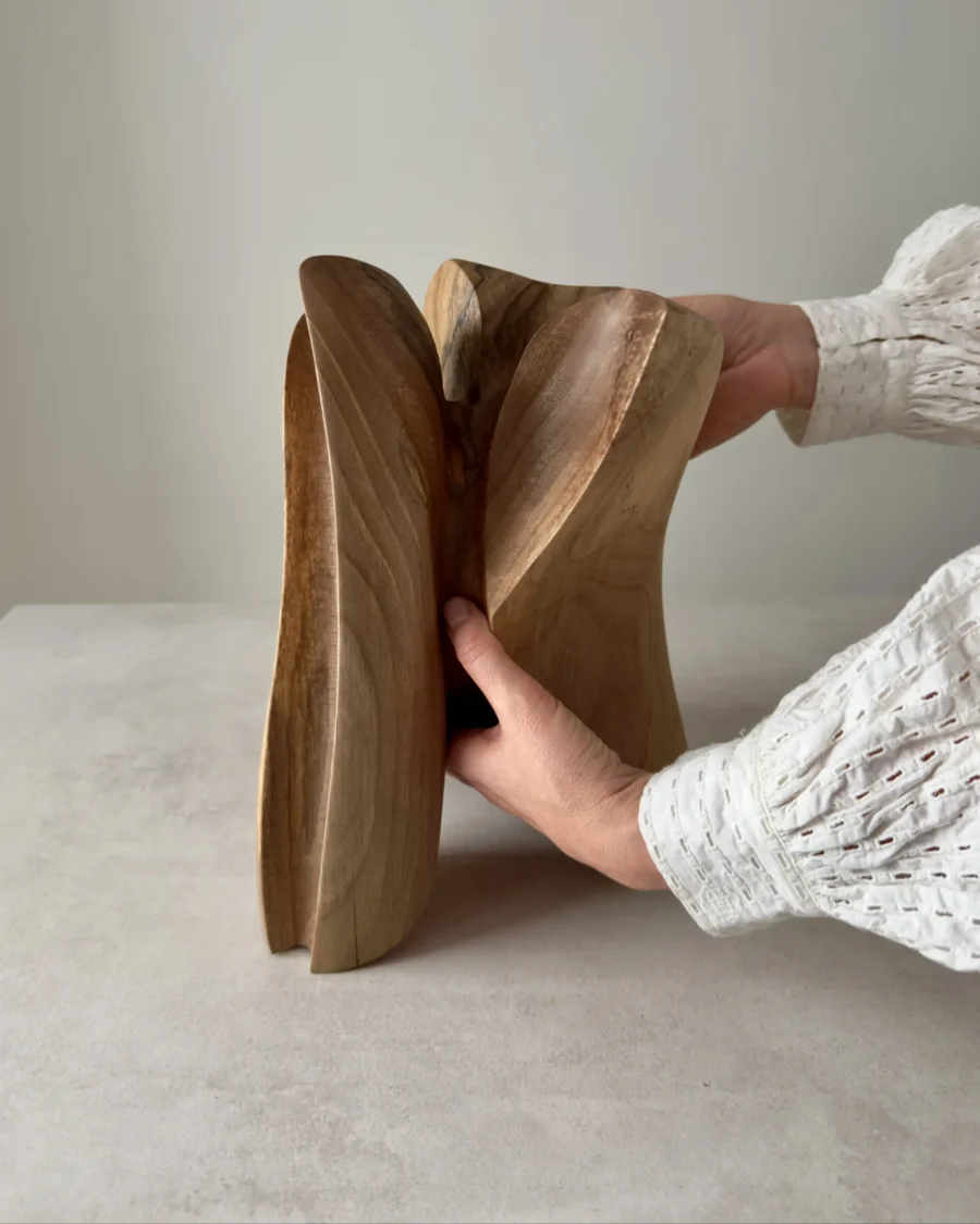 close view of hand interacting with abstract wood sculpture, showing size and organic shape