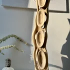 Tall abstract walnut wood sculpture Ivory Flow displayed in soft natural light with sculptural shadows on wall
