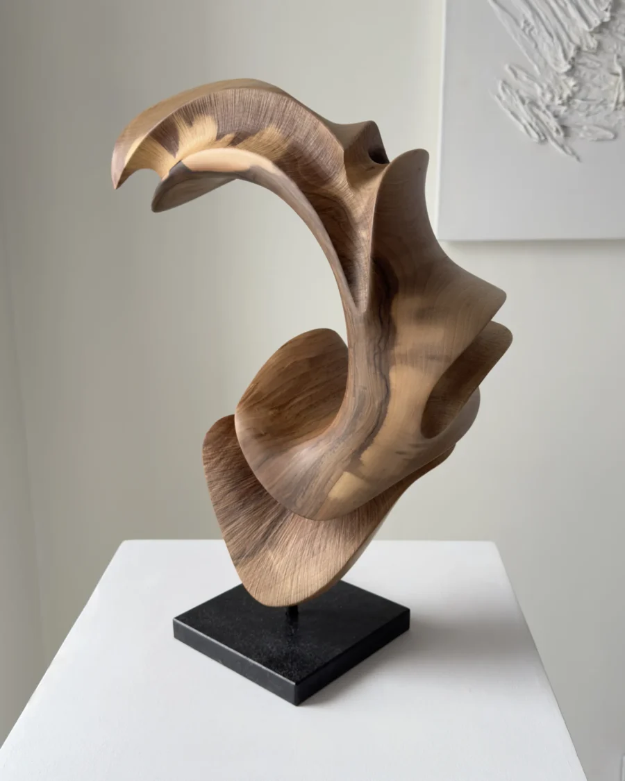 Side view of abstract wooden sculpture with open arc form and layered curves in aged walnut