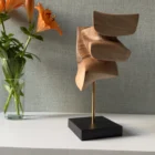 Abstract wood sculpture Velora placed in artistic interior with soft botanical background