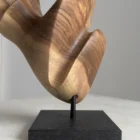 Close-up of hand-carved walnut sculpture showing grain, natural color variation, and smooth surface transitions