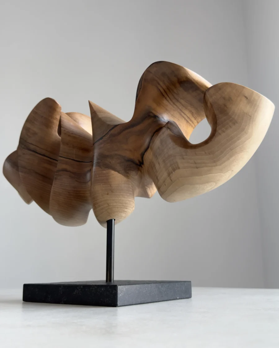 Abstract walnut wood sculpture side view revealing flowing organic form and horizontal composition