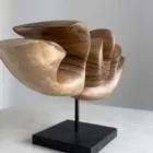 Hand carved walnut sculpture detail showing smooth transitions between light and shadow with natural wood grain