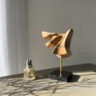 Abstract walnut wood sculpture Velora displayed in a minimalist interior with natural light and plant shadow