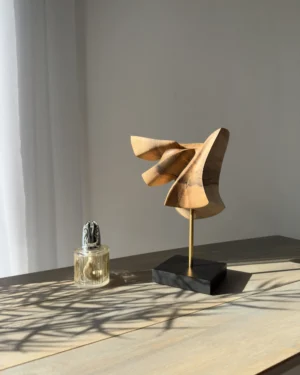 Abstract walnut wood sculpture Velora displayed in a minimalist interior with natural light and plant shadow
