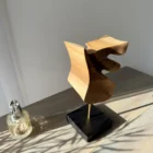 Walnut sculpture Velora with natural light casting dynamic shadows on surface and wall