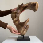 Hand holding abstract wood sculpture in walnut, showing scale and organic carved form