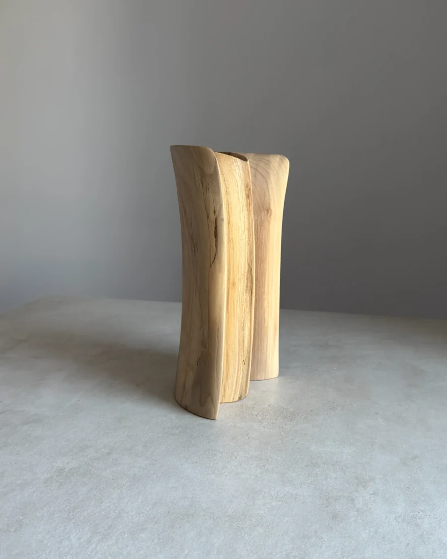 Side view of sculptural walnut vase, smooth carved surface and natural wood pattern