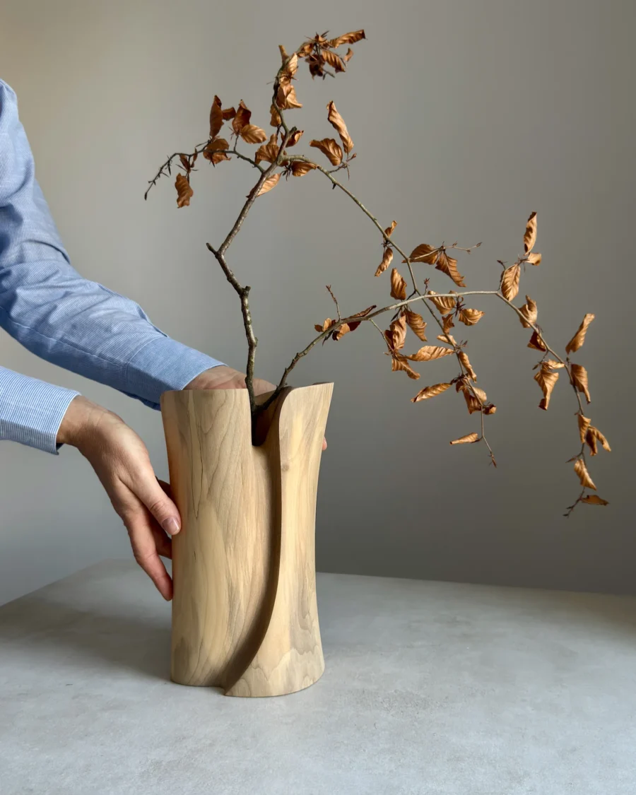 Wooden sculptural vase with dried branch, handmade walnut piece shown in human scale
