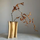 Hand-carved walnut wood vase with dried branch, minimalist sculptural form, natural grain detail