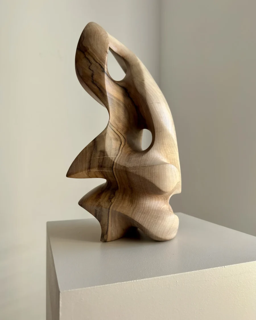 Side view of hand carved walnut sculpture with smooth flowing lines and natural wood grain