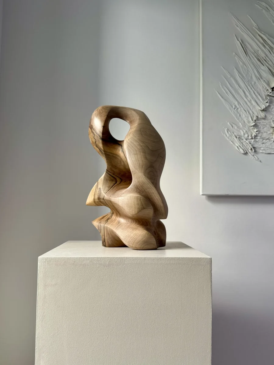 Side view of hand carved walnut sculpture with smooth flowing lines and natural wood grain
