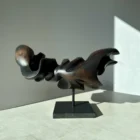 Dark Expansion hand-carved pear wood sculpture in strong natural light, showing its horizontal form and deep black carved recesses