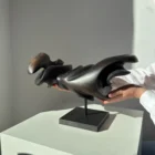 Dark Expansion pear wood sculpture held by the artist, showing the scale and three-dimensional character of the hand-carved form