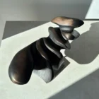 Dark Expansion abstract pear wood sculpture seen from above in direct sunlight, revealing layered carved surfaces and warm brown undertones