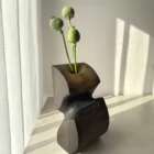 Ember Hollow hand-carved apple wood sculptural vase with poppy seed pods, shown in warm natural light with black waxed and natural wood surfaces.