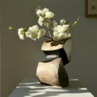 Artistic wooden vase styled with fresh flowers on neutral pedestal