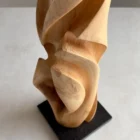 Detail of maple wood grain and smooth carved surface, black granite base
