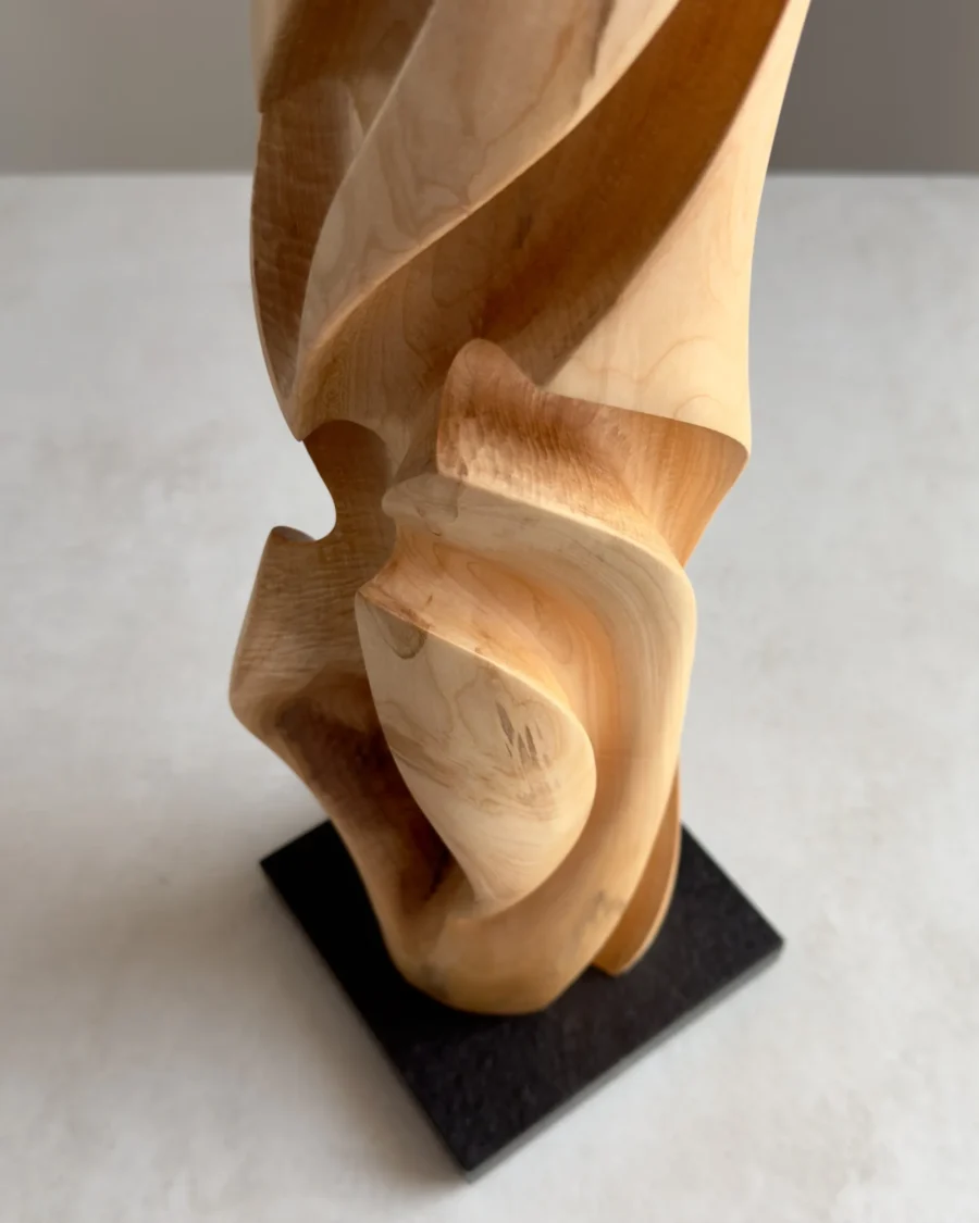 Detail of maple wood grain and smooth carved surface, black granite base