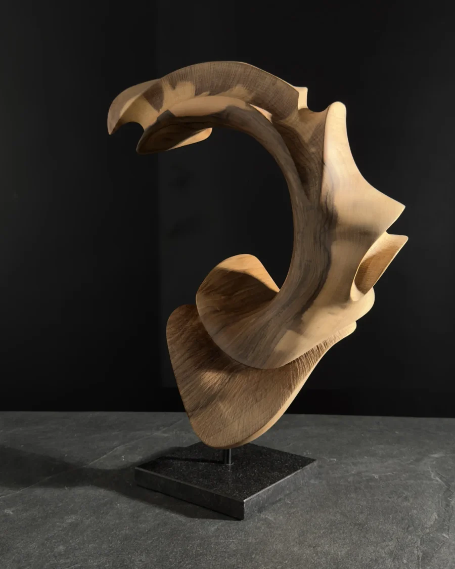 quiet-arc-walnut-wood-sculpture-main-ewebohome Hand carved walnut wood sculpture "Quiet Arc" on black background, abstract organic form with flowing curves and light shadow contrast