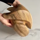 Close-up of a hand holding an abstract walnut sculpture, showing smooth surface and natural grain