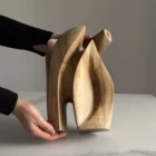 Hand holding a walnut wood sculpture to show scale and detail of the carved abstract form