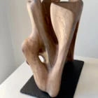 rebirth-wood-sculpture-slate-base-ewebohome Abstract sculpture with light passing through a hollow interior, creating shadow and depth.