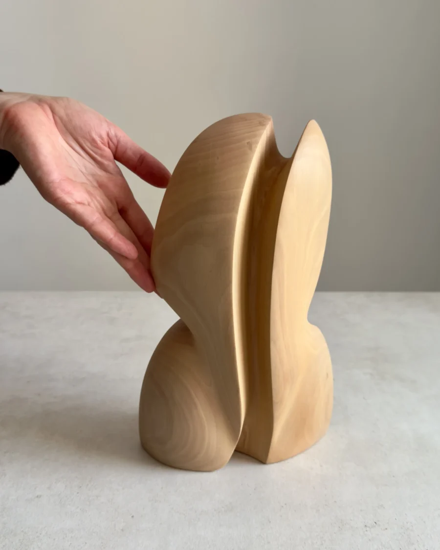 abstract wooden sculpture Seed Form shown back view with hand for scale