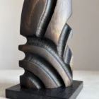 Close-up of Sentinel abstract beech wood sculpture showing polished granite base, repeating black carved recesses and contrasting warm wood tones