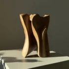 threefold-balance-abstract-walnut-sculpture-side-view Minimalist abstract walnut sculpture displayed on white pedestal in calm modern interior