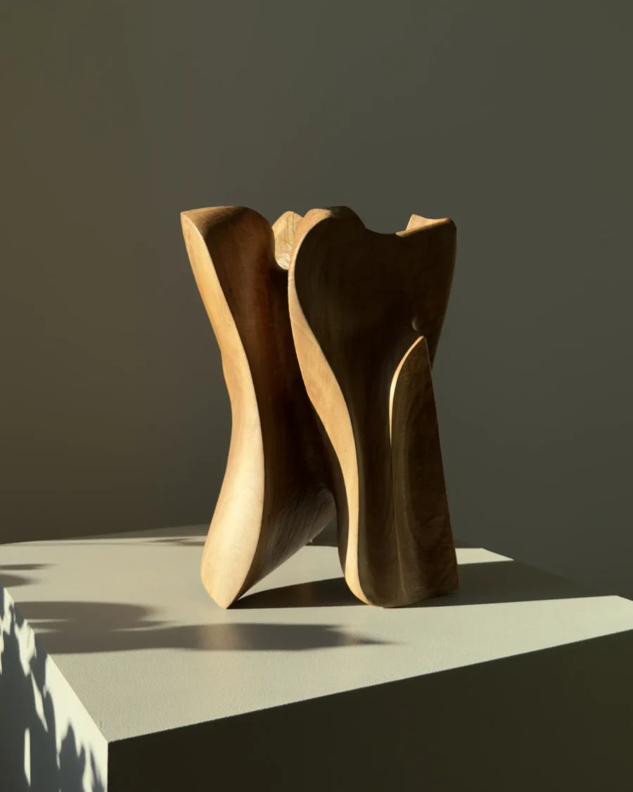 threefold-balance-abstract-walnut-sculpture-side-view Minimalist abstract walnut sculpture displayed on white pedestal in calm modern interior