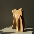 threefold-balance-modern-wood-artwork-organic-form Hand carved walnut sculpture illuminated by warm natural sunlight with soft interior shadows