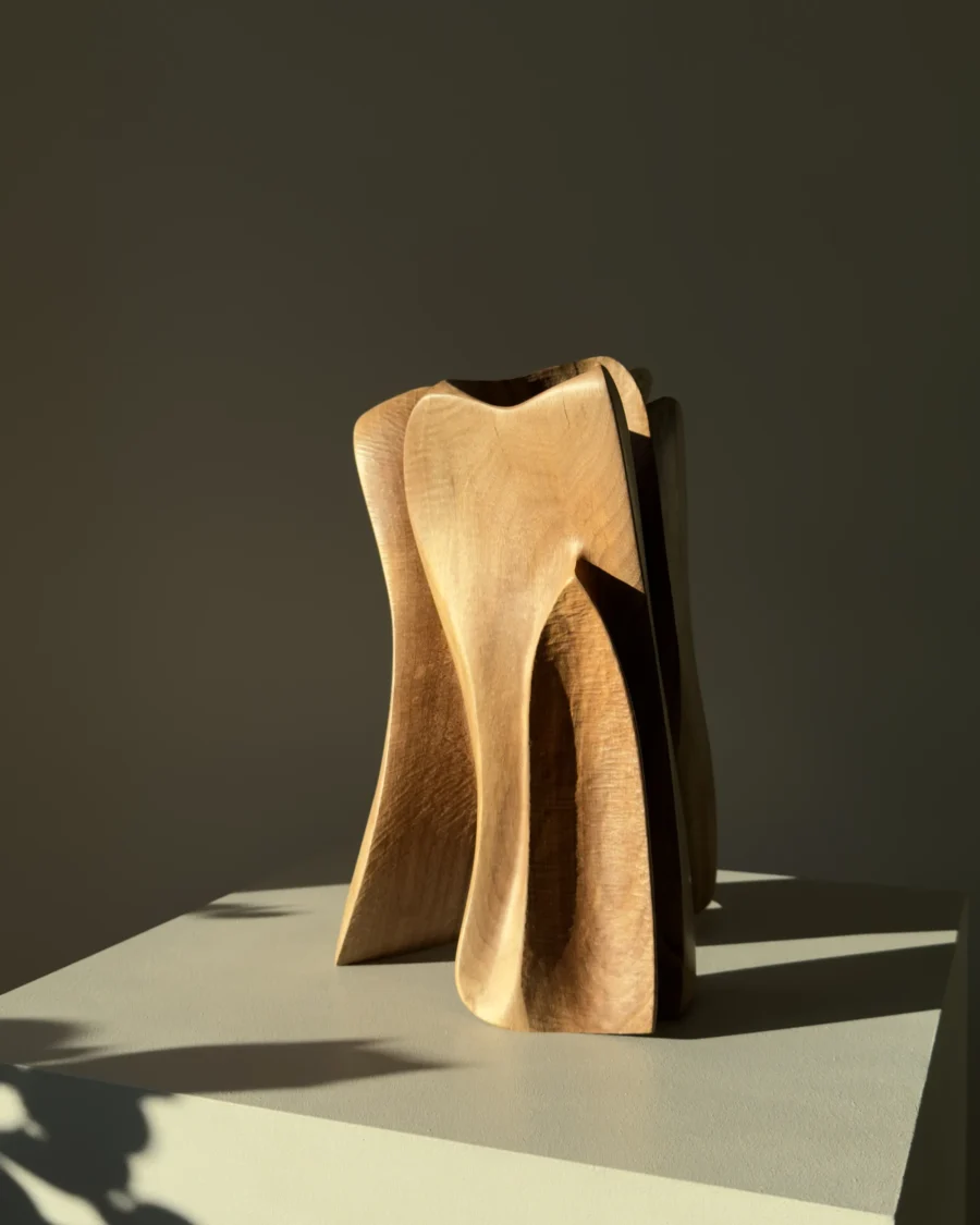 threefold-balance-modern-wood-artwork-organic-form Hand carved walnut sculpture illuminated by warm natural sunlight with soft interior shadows