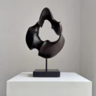 flame-memory-walnut-wood-sculpture-front-view-ewebohome Hand-carved walnut wood sculpture “Flame Memory” with fire-charred black surface on steel stand, front view in natural light