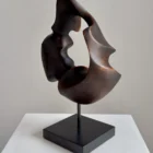 flame-memory-black-walnut-sculpture-minimalist-art Dark walnut wood sculpture with central opening and flowing organic form displayed on black base
