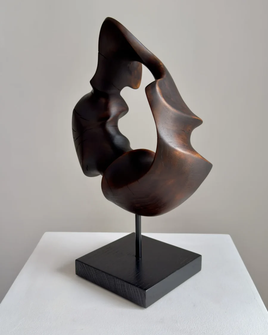 flame-memory-black-walnut-sculpture-minimalist-art Dark walnut wood sculpture with central opening and flowing organic form displayed on black base