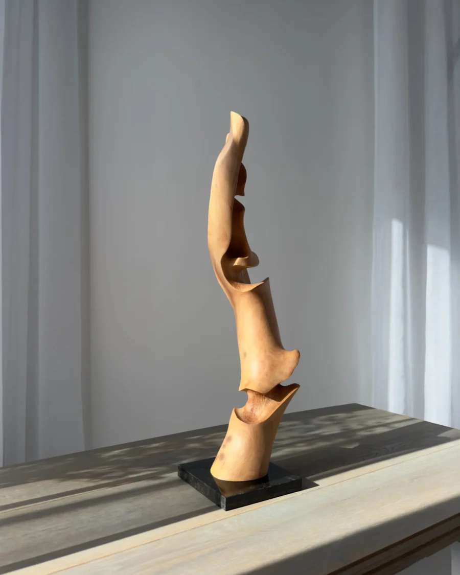 Vertical abstract wood sculpture in natural light minimalist setting wood table