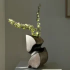 Hand carved apple wood sculptural vase with white flowers and dark textured interior in natural sunlight