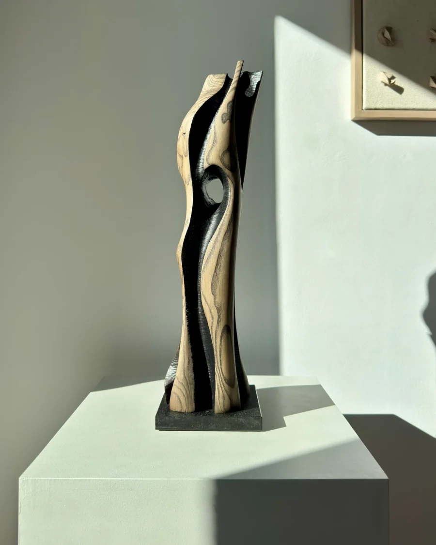 Back view of “Noctivis” hand-carved wood sculpture with flowing organic form and dark recessed interior surfaces.