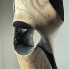 Close-up detail of “Noctivis” sculpture featuring circular opening, hand-carved textures, and contrast between black and natural wood surfaces.