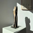 Minimalist abstract wood sculpture “Noctivis” displayed in soft natural sunlight with architectural shadow composition.