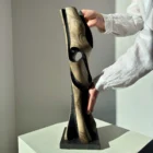 Artist holding “Noctivis” hand-carved wooden sculpture to show scale, texture, and natural light reflections.
