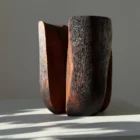 Contemporary wabi sabi wood vase with textured black surface and soft natural light