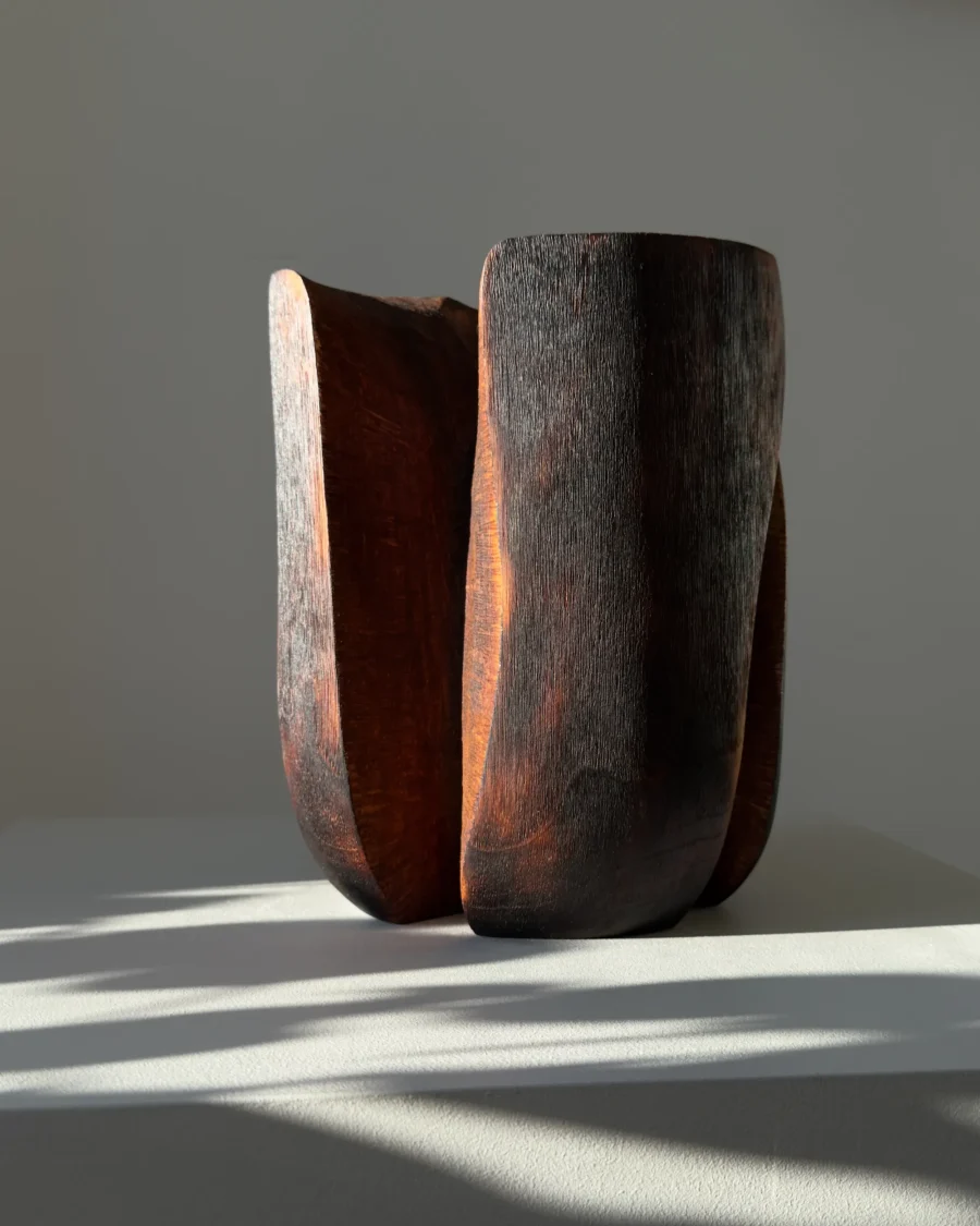 Contemporary wabi sabi wood vase with textured black surface and soft natural light