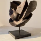 trace-of-fire-contemporary-sculpture Side profile of “Trace of Fire” hand-carved walnut sculpture with layered flowing shapes and warm sunlight reflections.
